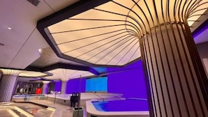A modern indoor swimming pool with a unique ceiling design, a jacuzzi, and a lounge area with seating. - Vest Holiday Hotel (Urumqi)