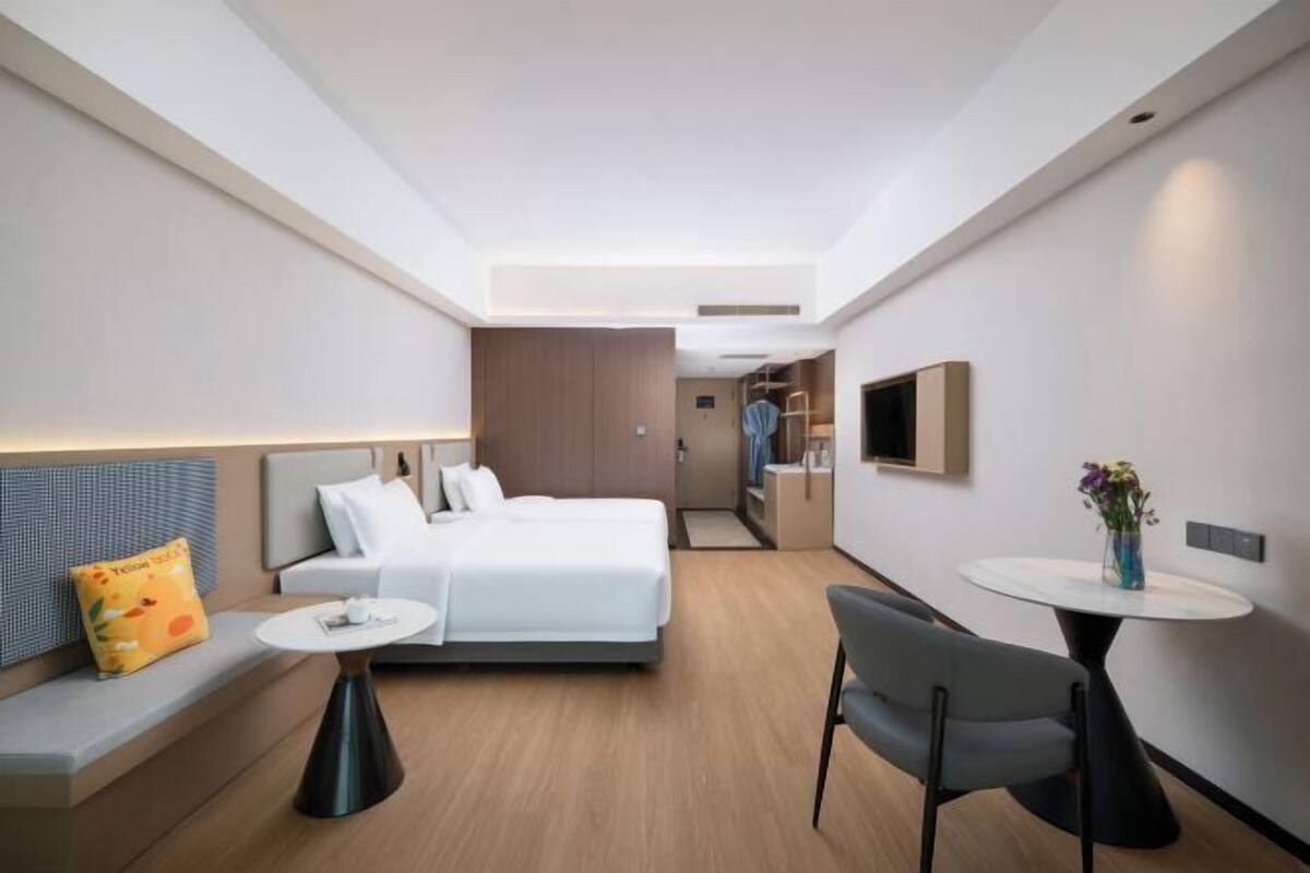 Ein modernes Hotelzimmer mit Bett, Sofa, Esstisch und Fernseher.