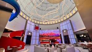 A spacious lobby with a modern design, featuring a large digital screen, comfortable seating areas, and a unique ceiling structure. - Vest Holiday Hotel (Urumqi)