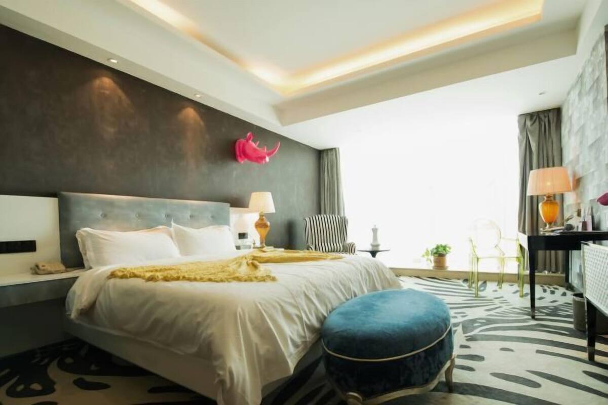 Ein modernes Hotelzimmer mit einem großen Bett, Nachttischlampen, einem Schreibtisch und Blick auf die Stadt.