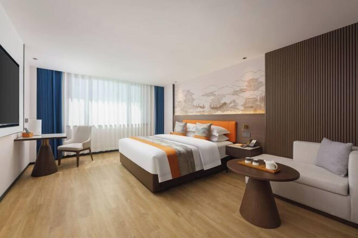 Ein modernes Hotelzimmer mit Bett, Schreibtisch, Sofa und Esstisch.