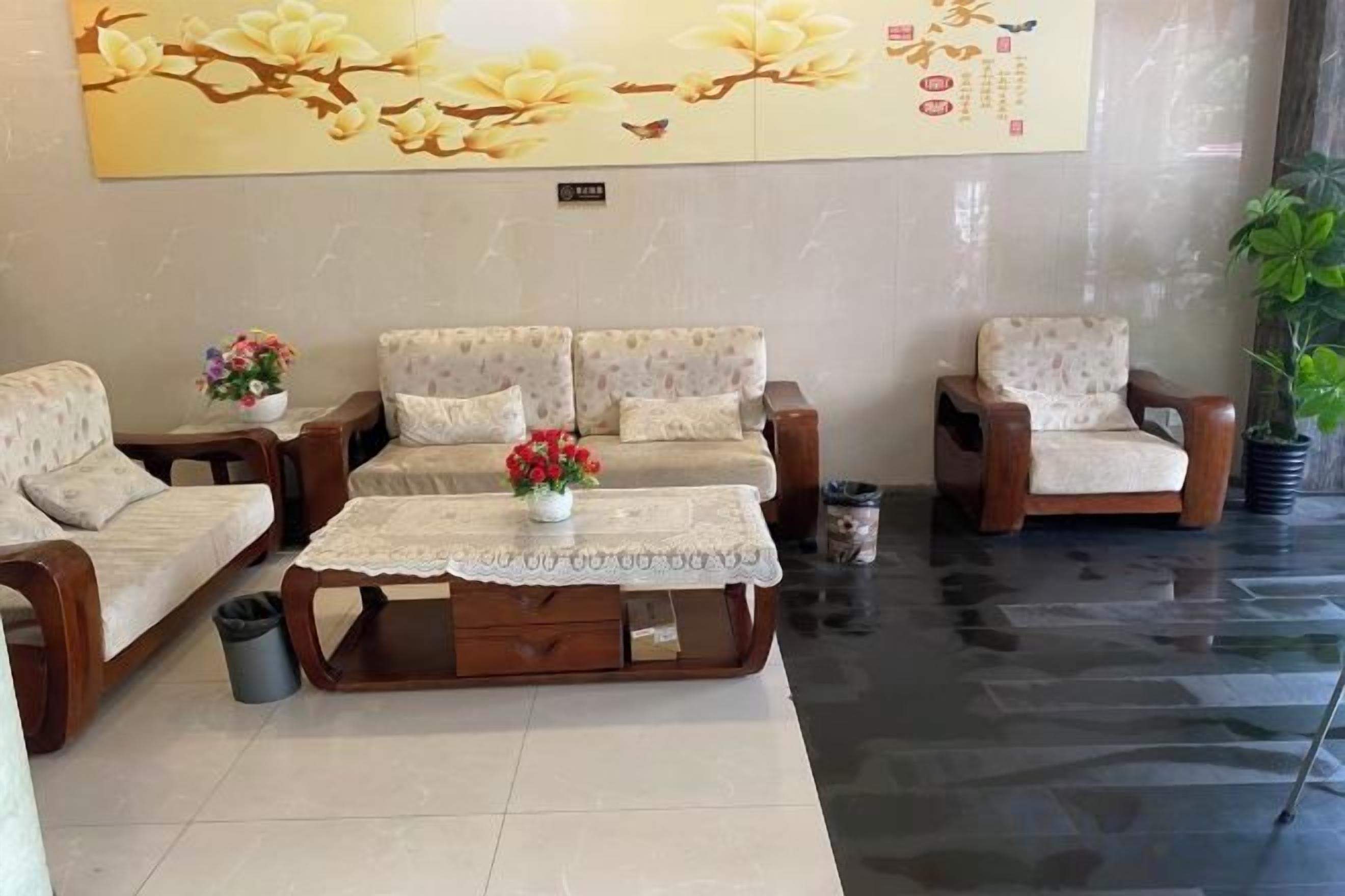 A lobby with a sofa set, a coffee table with flowers, and a potted plant.