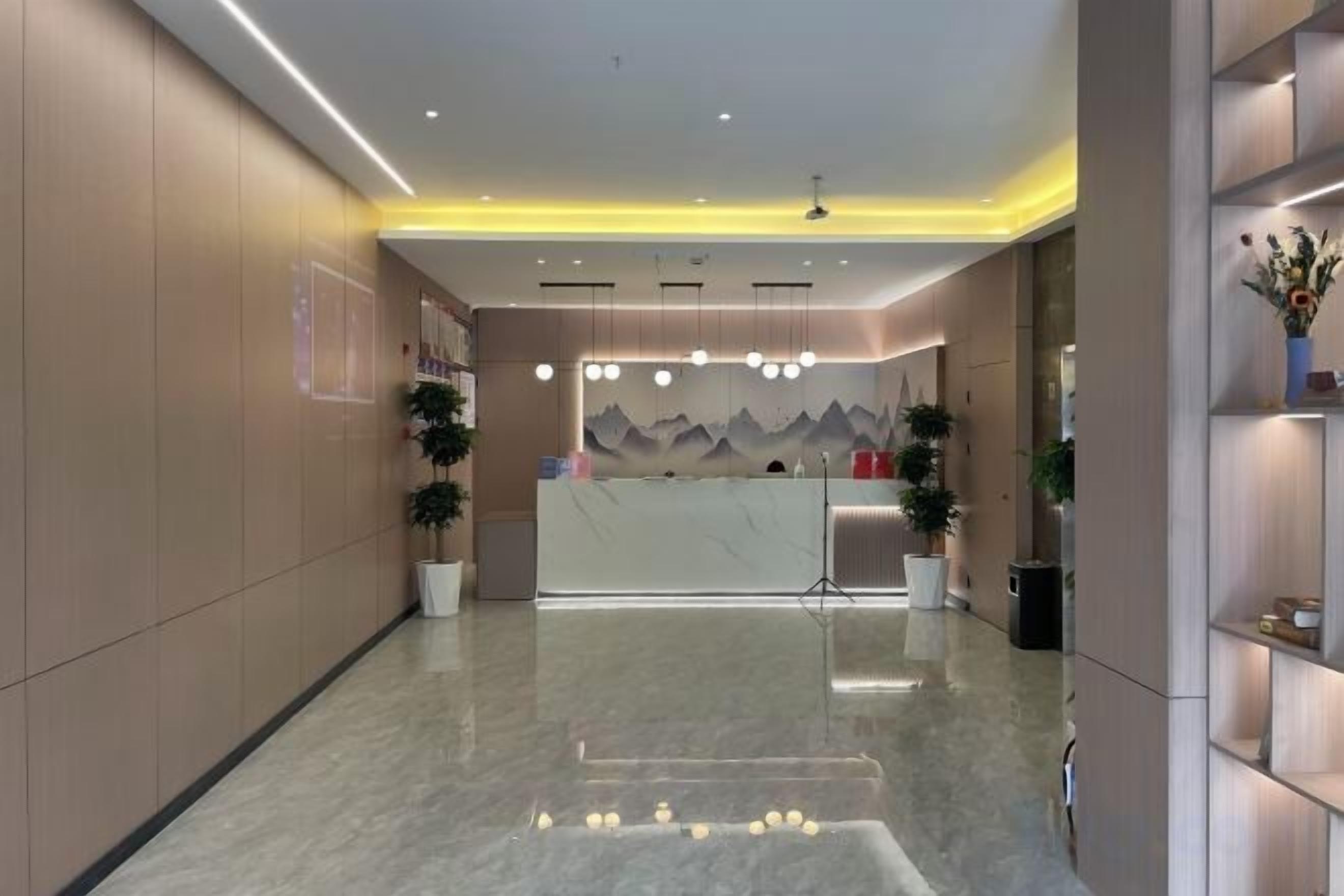 A hotel reception area with a marble floor, a reception desk, and a mountain mural on the wall.