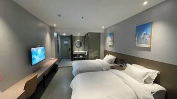 A hotel room with a bed, a desk, a television, and a bathroom visible through an open door.
