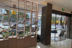 A reception area with a glass door, a metal partition with shelves, and a view of the street outside. - Taizhou 1981 Hotel (Sanmen Shangyang Road Branch) (Sanmen)