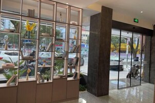 Zona de recepción con puerta de vidrio, separador metálico con estantes y vista a la calle.