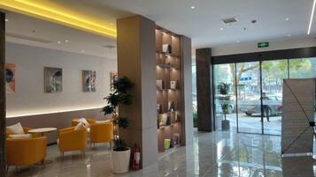 A hotel lobby with seating, a reception desk, and a large window.