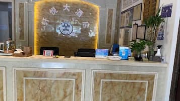 Un mostrador de recepción con acabado de mármol, un logotipo enmarcado y un código QR.