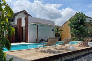 A modern pool area with lounge chairs and a glass-enclosed structure. - Likita Resort (Rayong City)