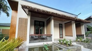 A modern building with a covered porch, a small water feature, and potted plants. - Likita Resort (Rayong City)
