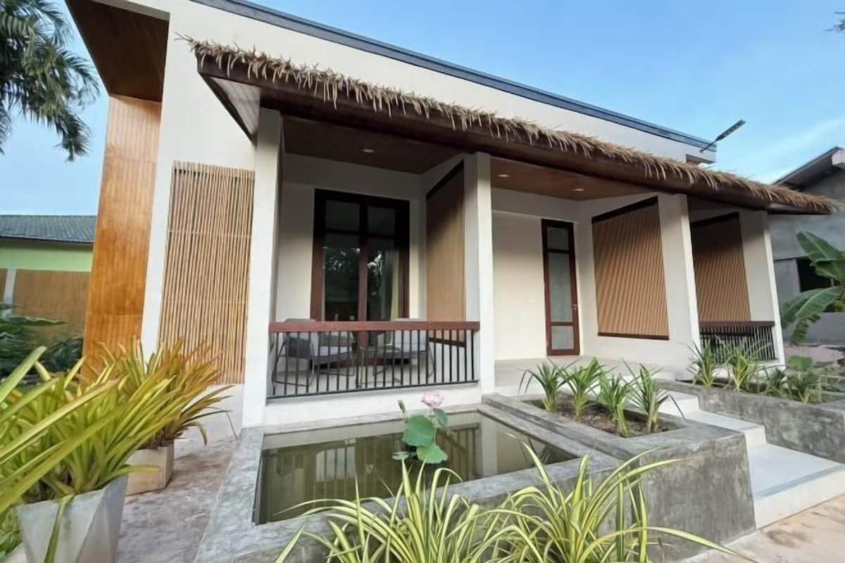 A modern building with a covered porch, a small water feature, and potted plants.