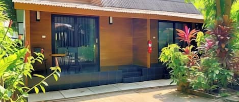 A modern building with a wooden facade, large glass windows, and a tiled entrance area.