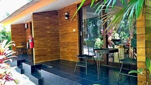 A modern outdoor area with a wooden structure, a fire extinguisher, and a table with chairs. - Likita Resort (Rayong City)