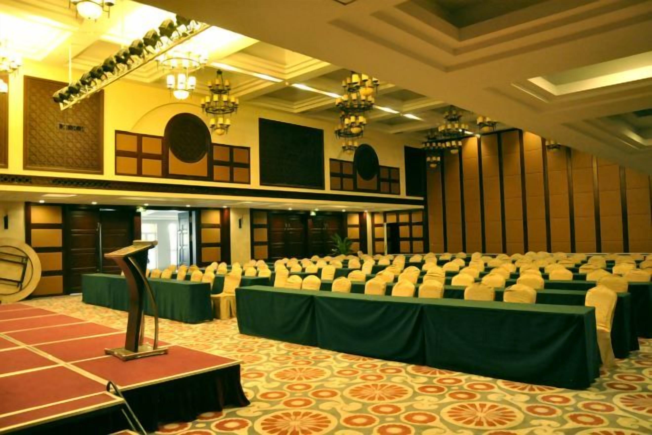 A conference room with rows of tables, a podium, and a carpeted floor.