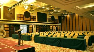 A conference room with rows of tables, a podium, and a carpeted floor.