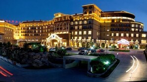 A multi-story hotel with a central courtyard, multiple balconies, and a well-lit facade.