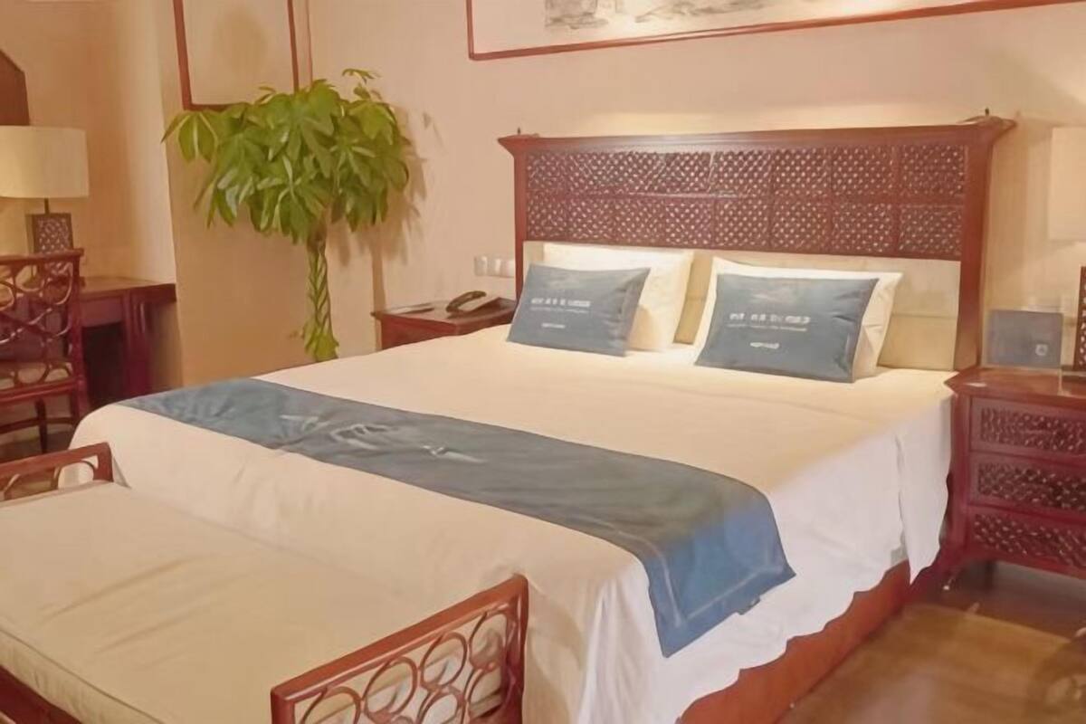 A neatly made bed with a blue bedspread, a wooden headboard, and two bedside tables with lamps.