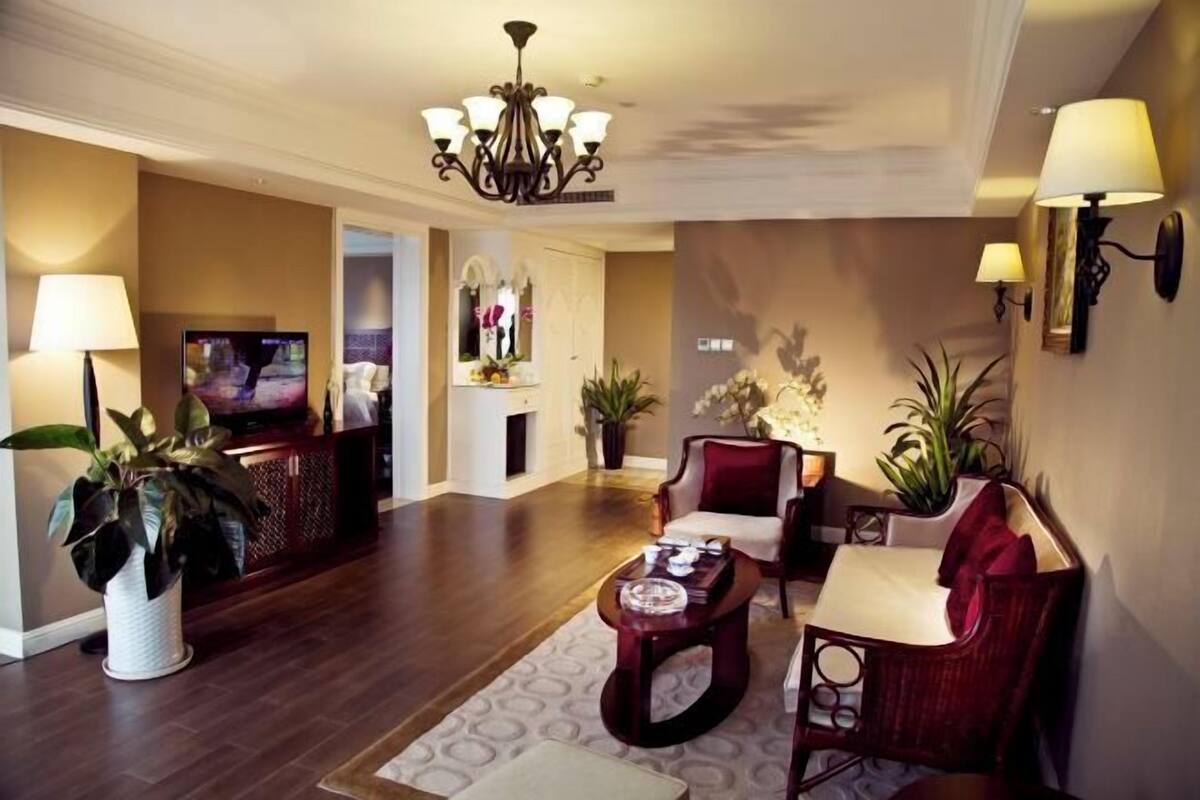 A living room with a TV, a chandelier, a sofa, and a coffee table.