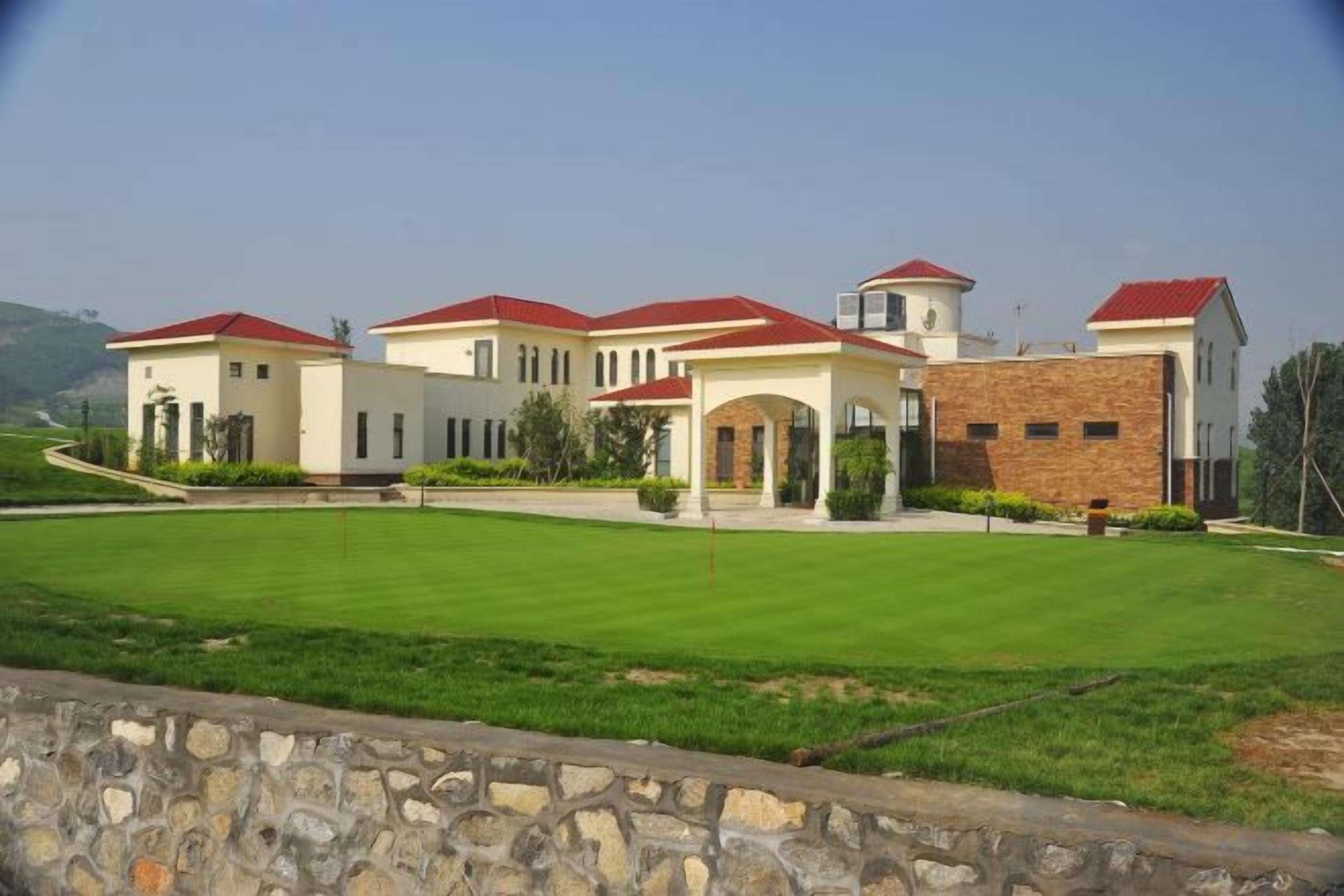 A large, multi-story building with a symmetrical facade, a central courtyard, and a stone wall in the foreground.