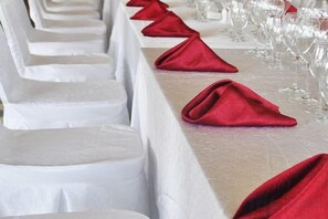 A row of white-covered chairs with red napkins on a table, suggesting a formal dining setting. - Zhongcheng Holiday Hotel (Shijiazhuang)