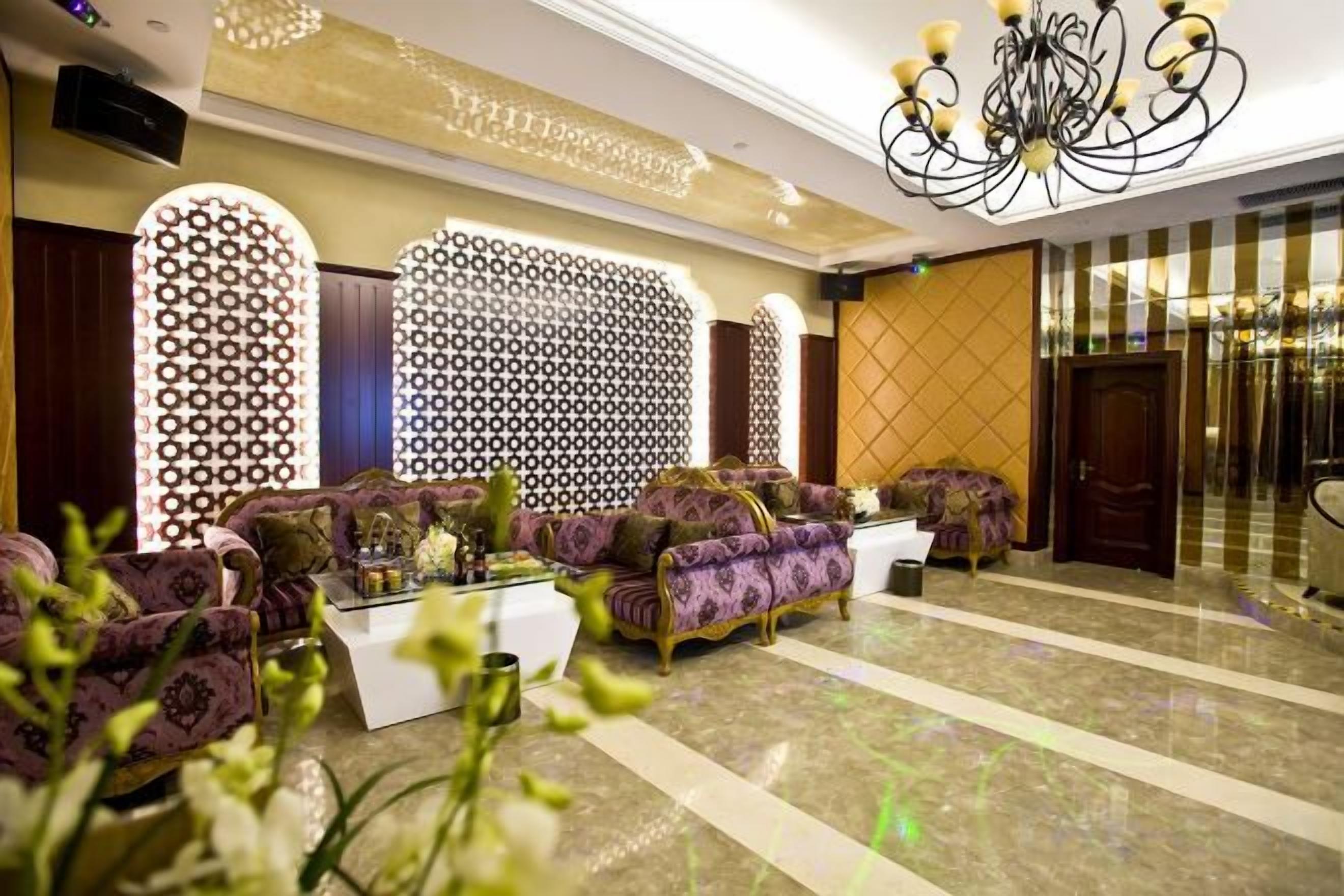 A lobby with a patterned wall, a chandelier, and a seating area with sofas.