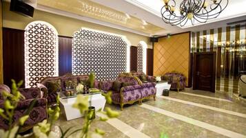 A lobby with a patterned wall, a chandelier, and a seating area with sofas.