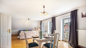 Un comedor con una mesa dispuesta para dos, un sofá y una ventana con cortinas.