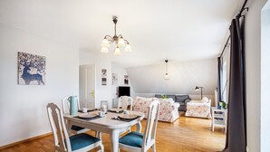 Una sala de estar moderna con comedor, un conjunto de sofás, una mesa de centro y una araña.