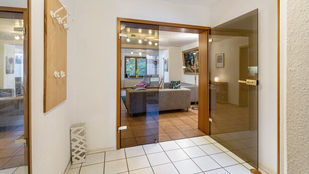 A modern interior with a sofa, a glass door, and a tiled floor. - Haus Sonneck - Apartment 5 with Mountain View, Private Terrace, and Wi-Fi (Willingen (Upland))