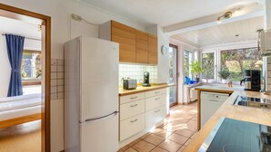 A modern kitchen with a refrigerator, wooden cabinets, a dishwasher, and a large island with a built-in stove. - Haus Sonneck - Apartment 5 with Mountain View, Private Terrace, and Wi-Fi (Willingen (Upland))