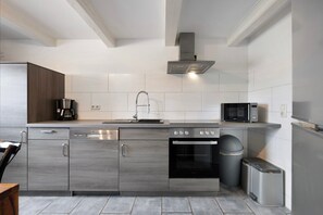 A modern kitchen with stainless steel appliances, a dishwasher, an oven, and a microwave. - Holiday Apartment 'Ferienhaus Op'n Doerp' with Private Terrace, Garden, Wi-Fi & EV Charger (Oesterwurth)