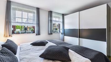 Ein modernes Hotelzimmer mit einem großen Bett, zwei Nachttischen, einem Kleiderschrank und einem Vorhangfenster.