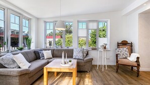 Ein modernes Wohnzimmer mit einem Ecksofa, einem Couchtisch aus Holz und einem Holzstuhl.