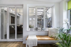 Una habitación con una banca, una ventana con vistas y una puerta corrediza.