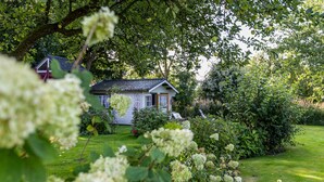 Ein Haus mit geneigtem Dach, umgeben von üppigem Grün und einem gepflegten Rasen.