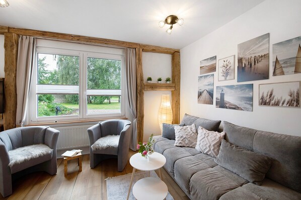 Ein gemütliches Wohnzimmer mit einem grauen Sofa, zwei Sesseln, einem kleinen Tisch und einem Kamin.