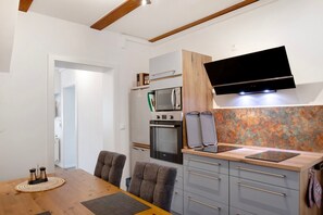 Una cucina moderna con televisore a schermo piatto, forno ventilato, microonde e un piano di lavoro in legno.