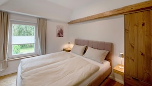Un dormitorio con cama, mesitas de noche, una ventana y un armario.