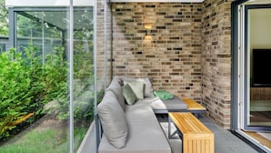 Een modern buitgedeelte met een bank, kussens en een houten tafel.
