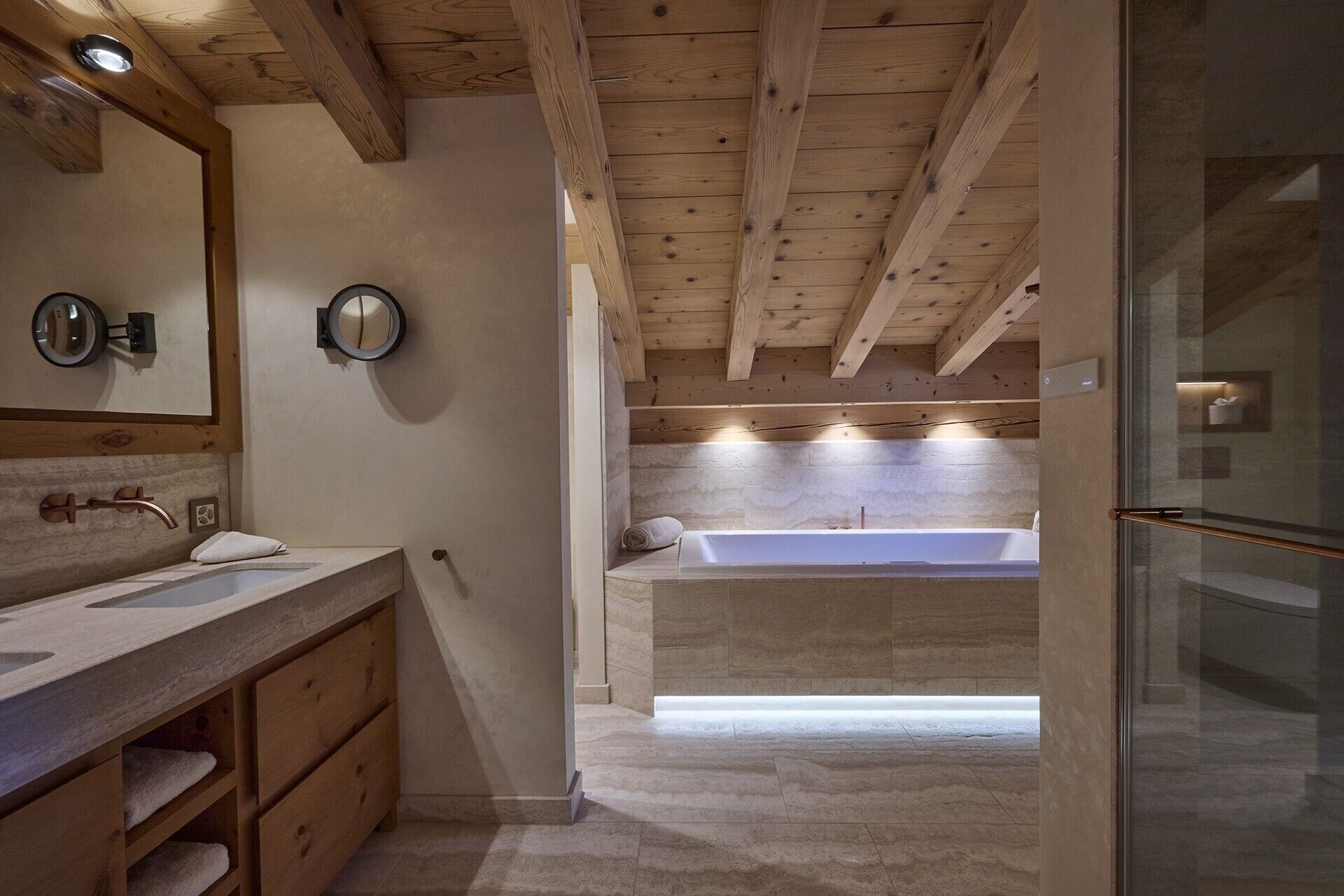 Une salle de bain avec des poutres en bois, une baignoire et un meuble-lavabo doté d’un miroir et d’un porte-serviettes.