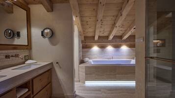 Une salle de bain avec des poutres en bois, une baignoire et un meuble-lavabo doté d’un miroir et d’un porte-serviettes.