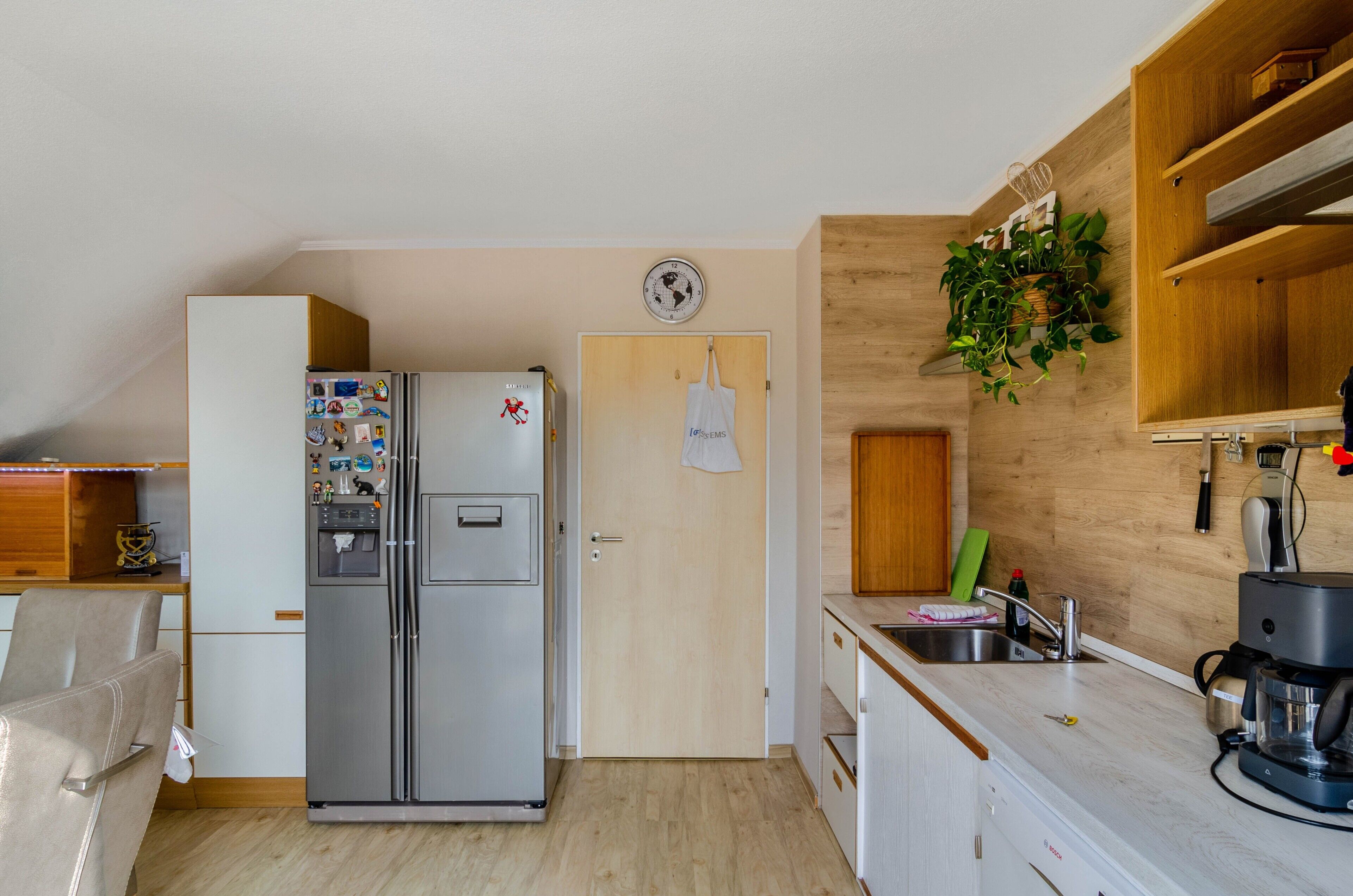 A compact kitchen with a refrigerator, a sink, and wooden cabinetry.