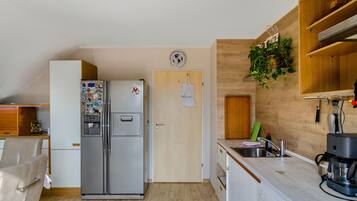 A compact kitchen with a refrigerator, a sink, and wooden cabinetry.