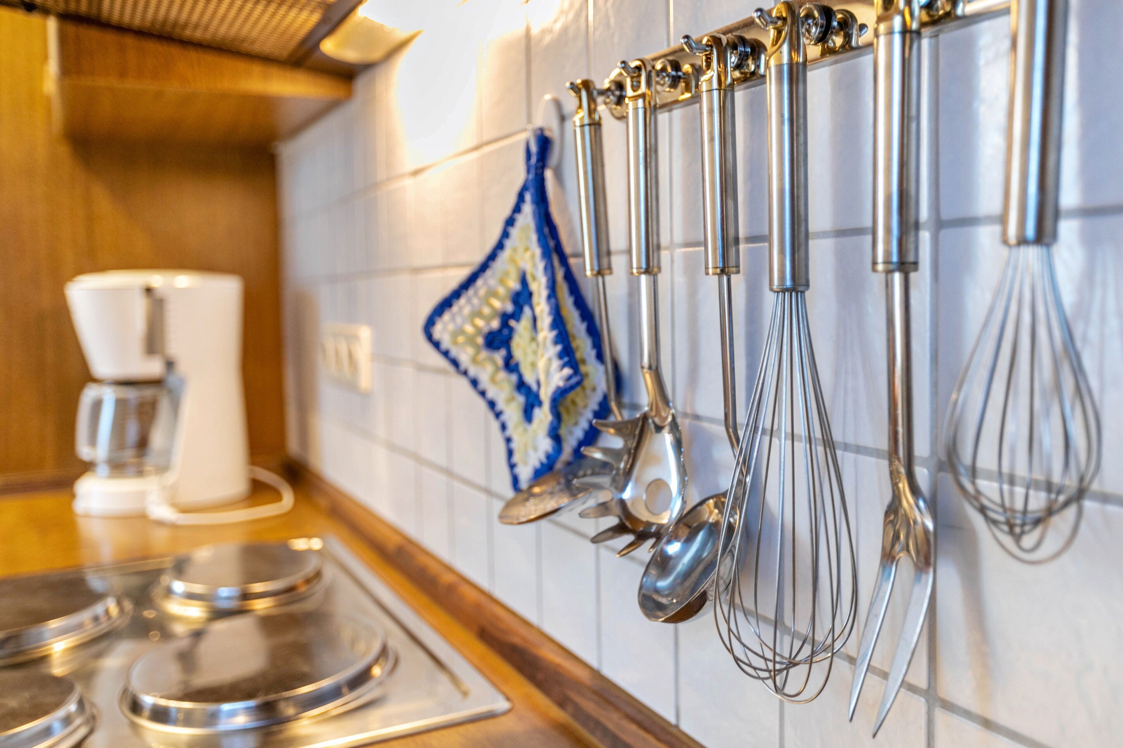 A kitchen with stainless steel appliances, a coffee maker, and utensils hanging on the wall.