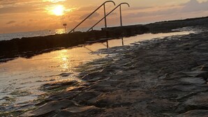 A rocky shoreline with a metal staircase leading down to the water.