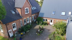 A courtyard with a brick house, a gravel driveway, and a satellite dish.