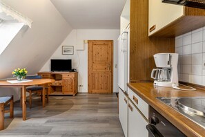 Kompakti keitti ö, jossa on puiset kaapit, kahvinkeitin ja sisäänrakennettu uuni.