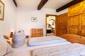 Une chambre à coucher avec un lit en bois, une armoire en bois, une commode en bois et une petite table de chevet avec une lampe.