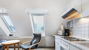 Una cocina compacta con estufa, microondas y un pequeño comedor con mesa y sillas.