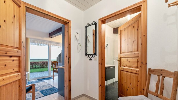 Een houten interieur met een bank, een spiegel en een deur naar een balkon.